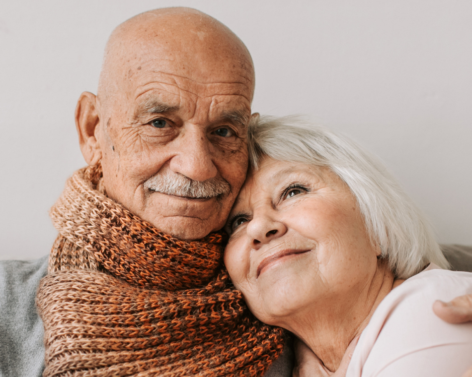 An older couple embraces, showing love and support, while doctors provide home care assistance