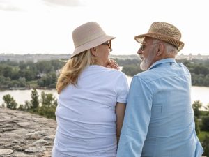 Elderly couple enjoying scenic river view from rock perch